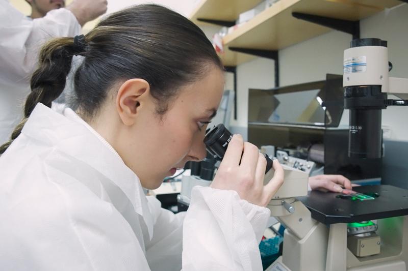 Female PDD student looking through microscope
