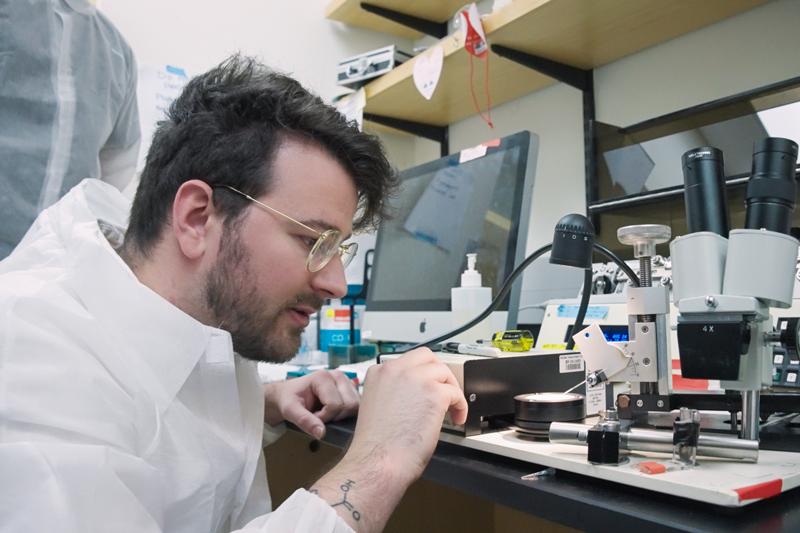 PDD student at lab closely inspecting something