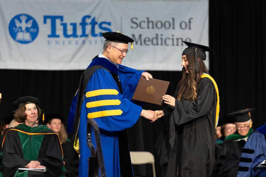 Dean Michael Chin handing a diploma to a masters student.