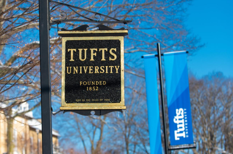 Two Tufts University signs outdoors against a blue sky