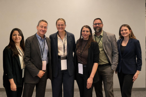 Six people on the Center for the Study of Drug Development team stand together in front of a wall